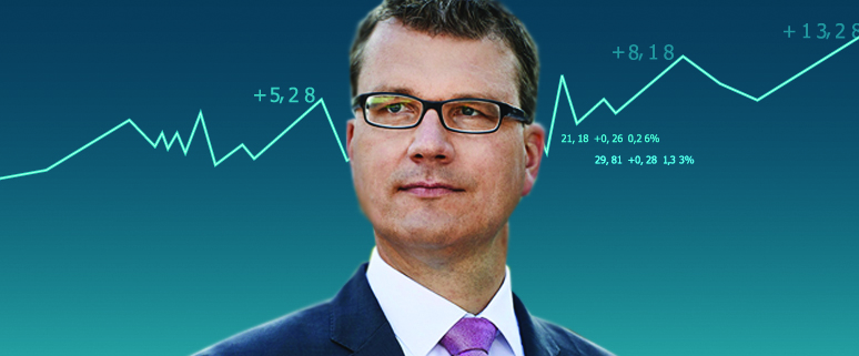 Ein Mann in Anzug und Brille steht vor einem Hintergrund mit einem ansteigenden Finanzdiagramm.