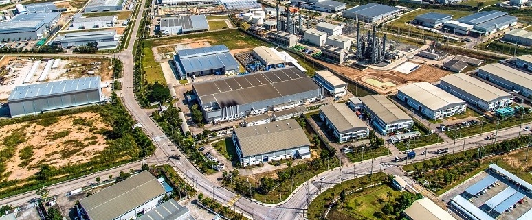 Luftaufnahme eines Industriegebiets mit mehreren Fabrikgebäuden, Straßen und Grünflächen.