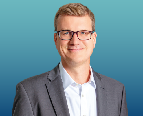 Auf dem Bild sieht man Chefvolkswirt Carsten Mumm mit grauem Sakko, weißem Hemd und freundlichem Blick in die Kamera.