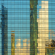 Glasfassade eines Hochhauses mit Spiegelung der Skyline verschiedener Wolkenkratze