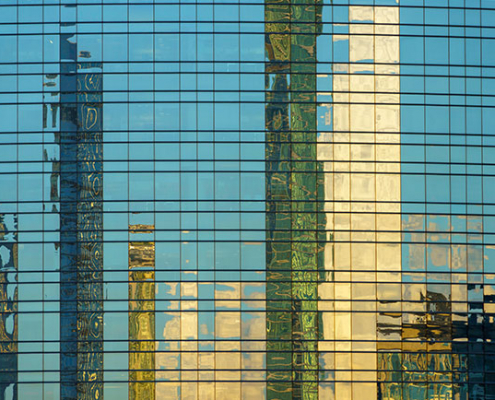 Glasfassade eines Hochhauses mit Spiegelung der Skyline verschiedener Wolkenkratze