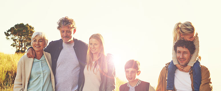 Das Bild zeigt eine fröhliche Familie mit Vater, Mutter, Kind und Großmutter bei einem gemeinsamen Nachmittagsspaziergang durch die Natur.