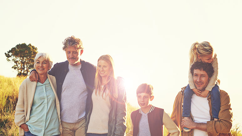 Das Bild zeigt eine fröhliche Familie mit Vater, Mutter, Kind und Großmutter bei einem gemeinsamen Nachmittagsspaziergang durch die Natur.