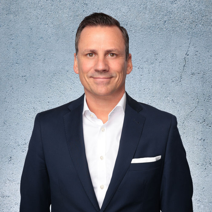 Auf dem Bild sieht man Thomas Nerlinger mit einem Dunklen Anzug und weißem Hemd