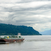 Tanker auf dem Meer vor einer Meerenge mit durchwachsener teils gewittriger, teils aufgerissener Wolkendecke
