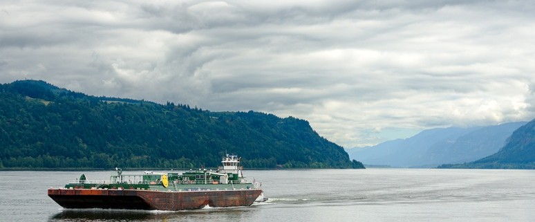 Tanker auf dem Meer vor einer Meerenge mit durchwachsener teils gewittriger, teils aufgerissener Wolkendecke