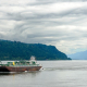 Tanker auf dem Meer vor einer Meerenge mit durchwachsener teils gewittriger, teils aufgerissener Wolkendecke