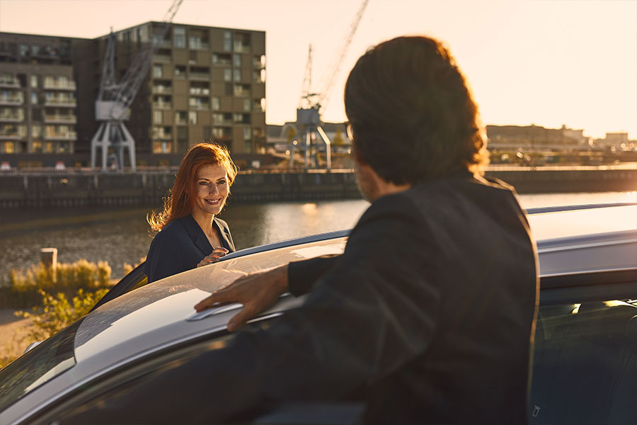 Eine Frau und ein Mann stehen an ihrem Auto. Im Hintergrund sieht man die Hafencity in Hamburg